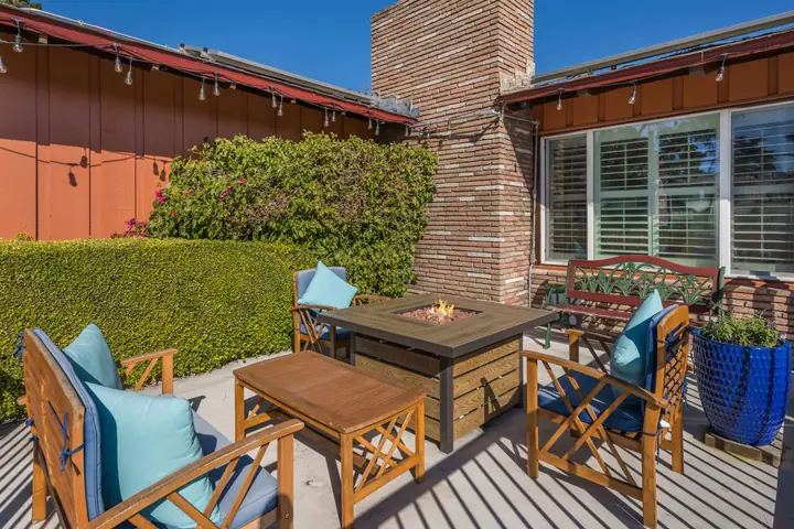 Patio with wooden armchairs, blue cushions and a fire table beside the inn's brick chimney